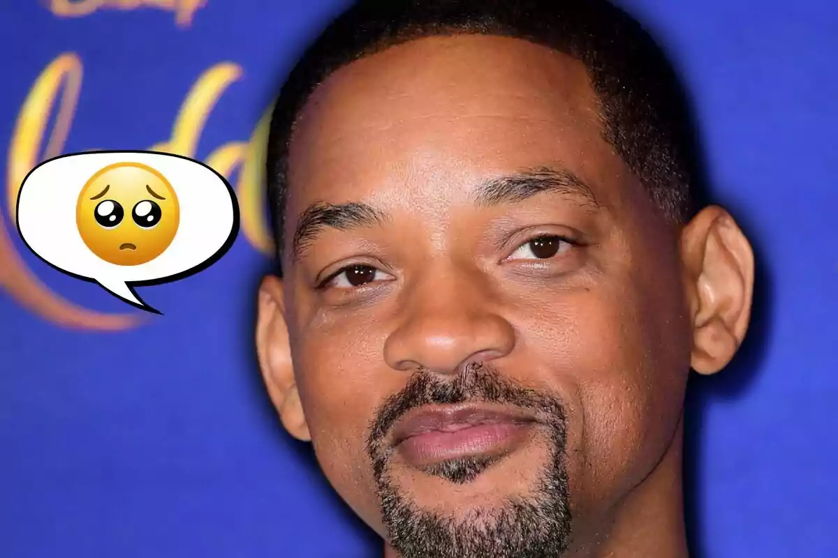 Primer pla d’un home amb expressió seriosa i un globus de diàleg amb un emoji de carona trista sobre fons blau Primer pla d’un home amb expressió seriosa i un globus de diàleg amb un emoji de carona trista sobre fons blau