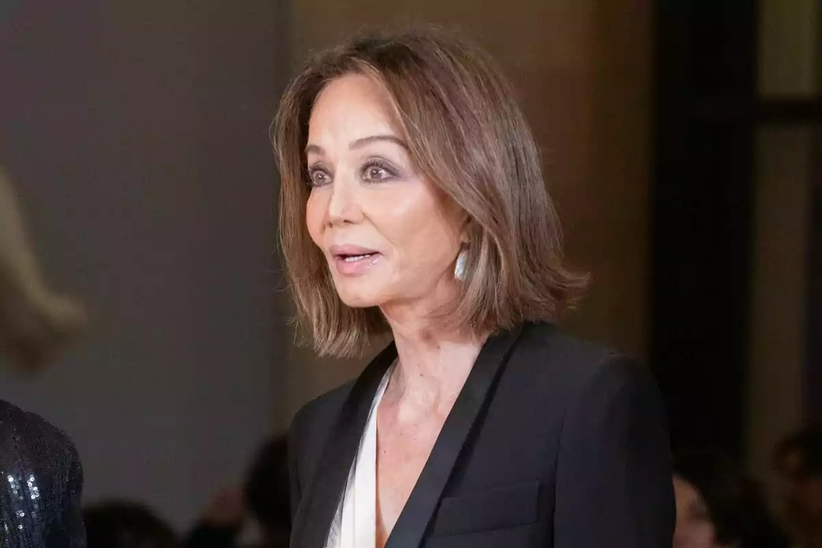 Dona de cabell castany curt i llis amb jaqueta negra i brusa clara en un esdeveniment formal