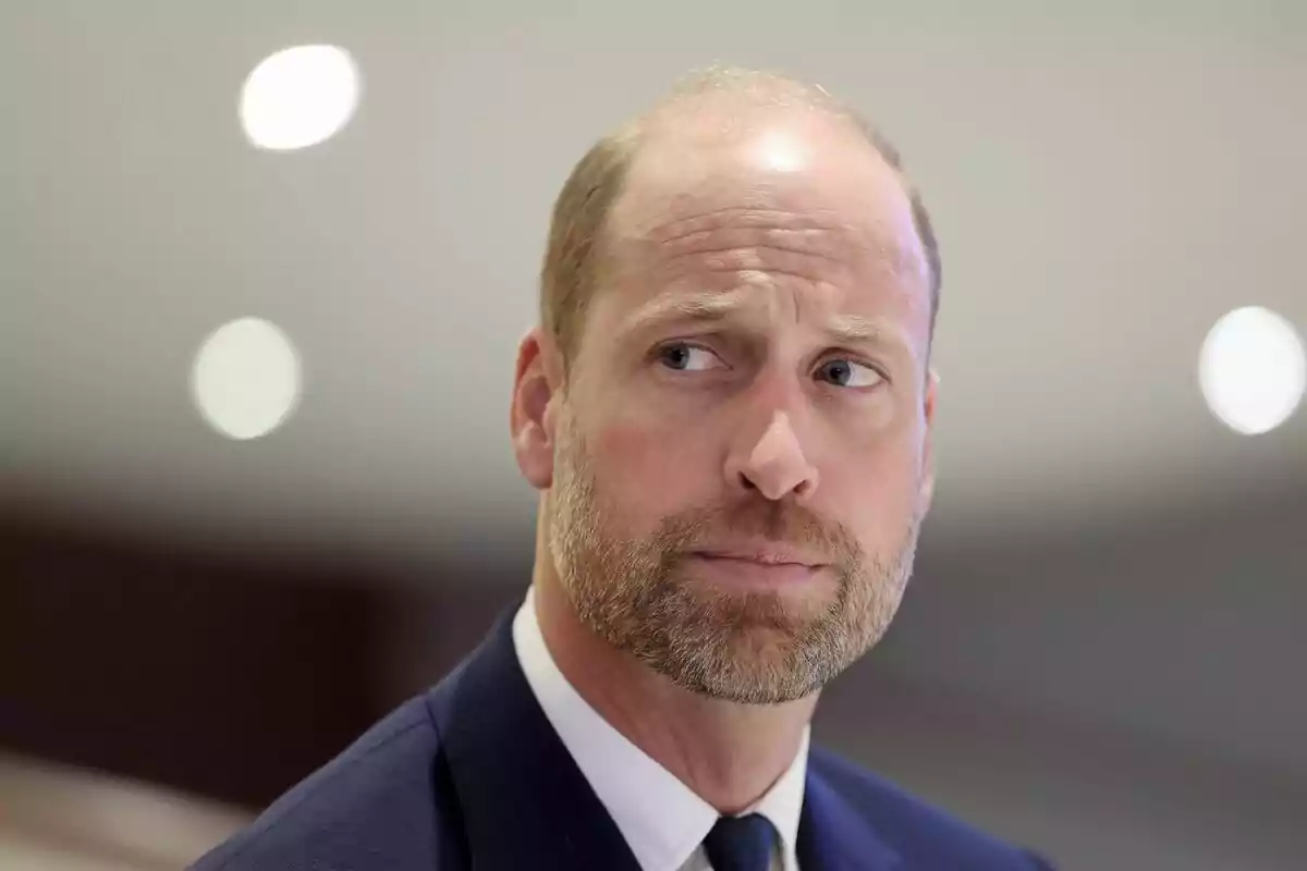 Home amb vestit i expressió seriosa mirant cap a un costat en un ambient interior il·luminat Home amb vestit i expressió seriosa mirant cap a un costat en un ambient interior il·luminat