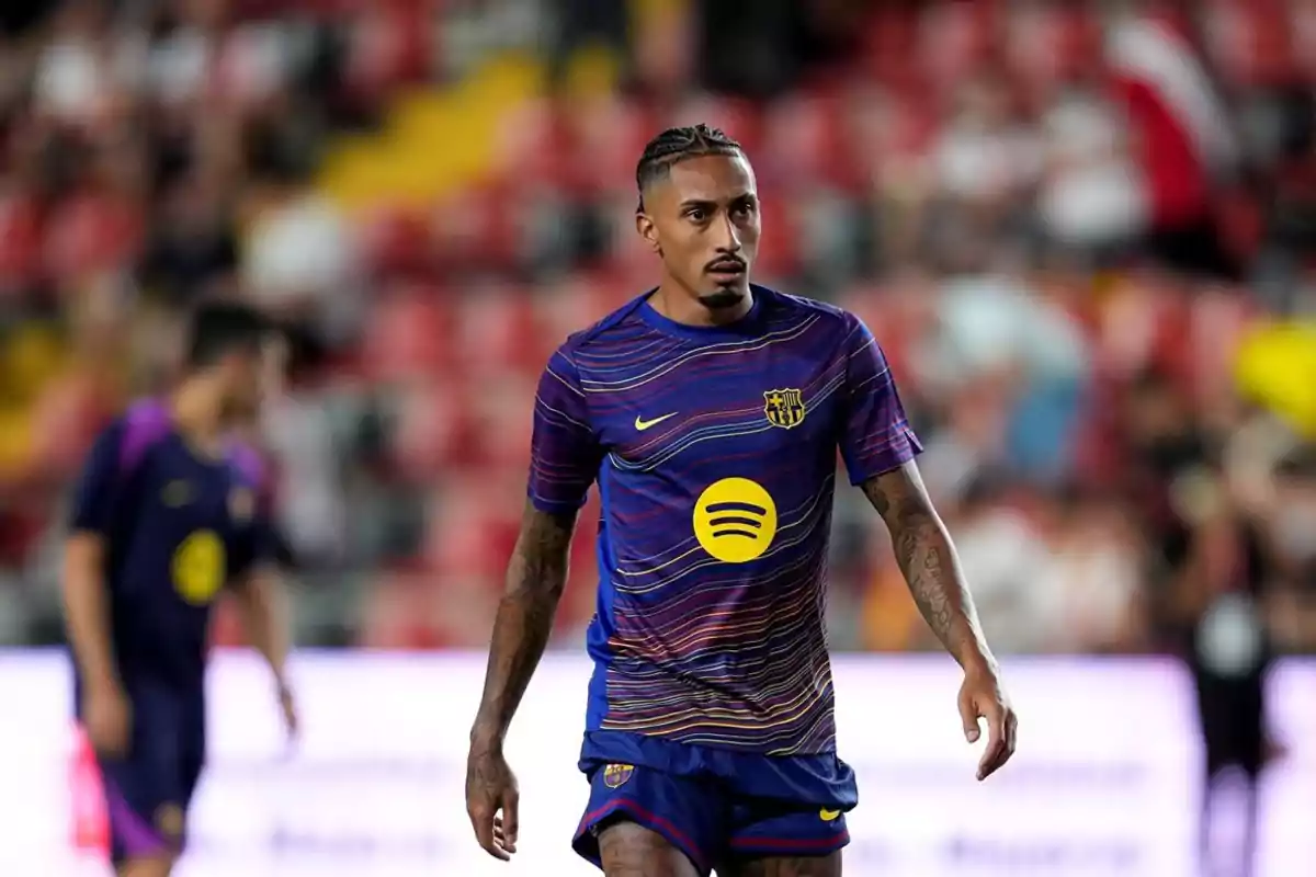 Futbolista del FC Barcelona amb uniforme d’escalfament blau i detalls grocs durant un partit en un estadi Futbolista del FC Barcelona amb uniforme d’escalfament blau i detalls grocs durant un partit en un estadi