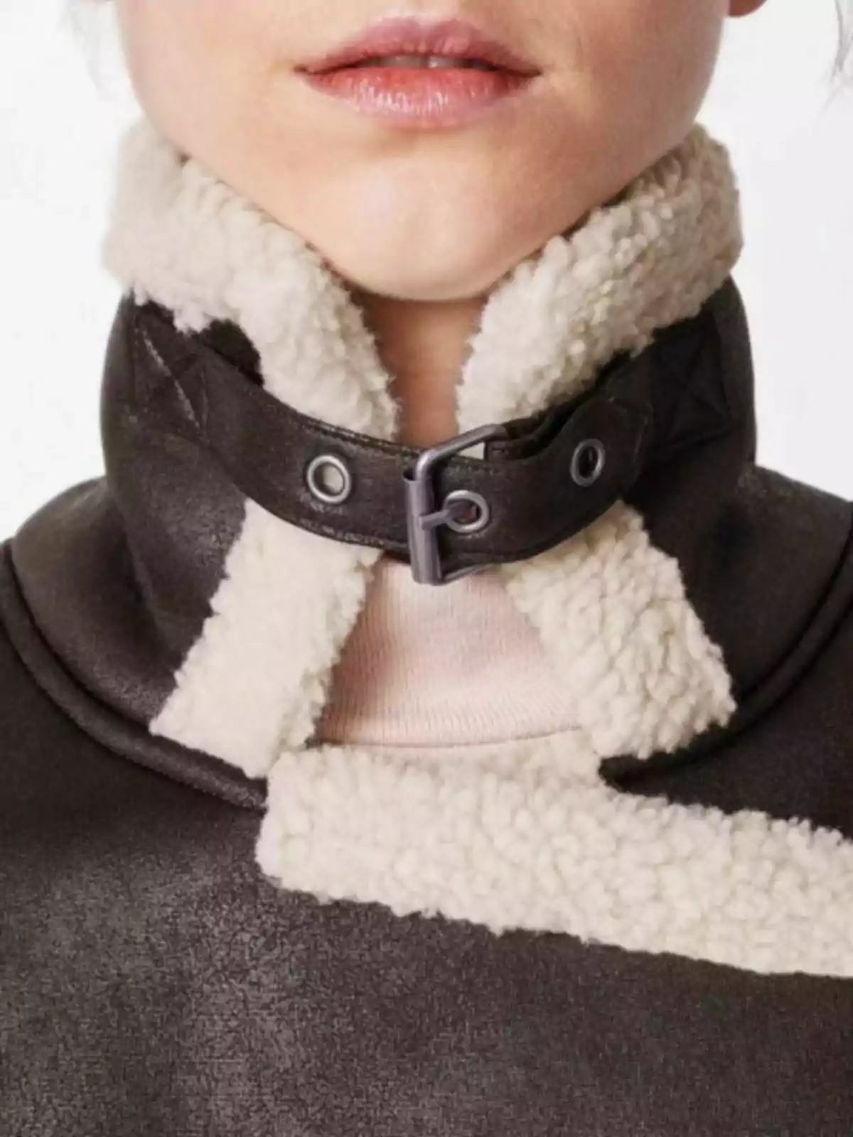 Persona amb una jaqueta de borrego amb coll alt i sivella metàl·lica Persona amb una jaqueta de borrego amb coll alt i sivella metàl·lica