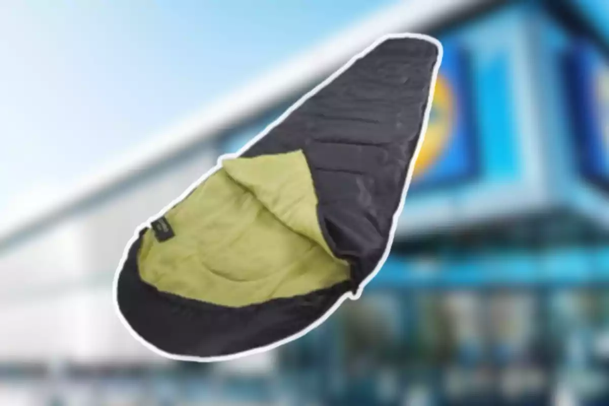 Saco de dormir negre amb interior verd clar davant d’un edifici desenfocat Saco de dormir negre amb interior verd clar davant d’un edifici desenfocat