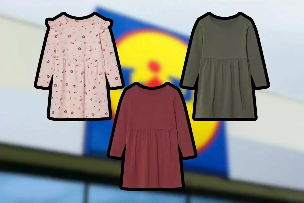 Tres vestidos infantiles de manga larga en diferentes colores y estampados sobre un fondo desenfocado de una tienda