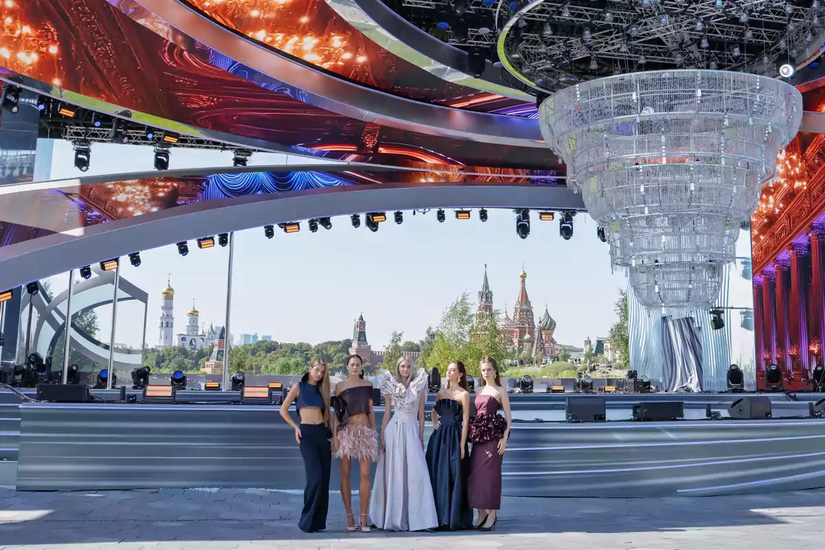 Cinco mujeres posan con vestidos elegantes frente a un escenario moderno al aire libre con la catedral de San Basilio y la torre del Kremlin al fondo Cinco mujeres posan con vestidos elegantes frente a un escenario moderno al aire libre con la catedral de San Basilio y la torre del Kremlin al fondo