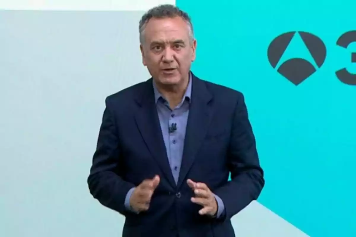 Roberto Brasero vestit amb un vestit blau parlant davant d’una pantalla blava amb logotips geomètrics.