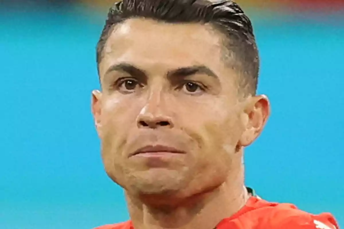 Primer pla de Cristiano Ronaldo amb expressió seriosa i cabell curt pentinat cap enrere, vestint una samarreta vermella sobre un fons blau desenfocat Primer pla de Cristiano Ronaldo amb expressió seriosa i cabell curt pentinat cap enrere, vestint una samarreta vermella sobre un fons blau desenfocat