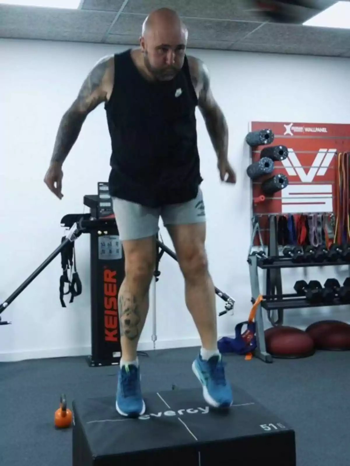 Kiko Rivera amb samarreta negra i pantalons curts grisos fent un salt pliomètric sobre una caixa en un gimnàs Kiko Rivera amb samarreta negra i pantalons curts grisos fent un salt pliomètric sobre una caixa en un gimnàs