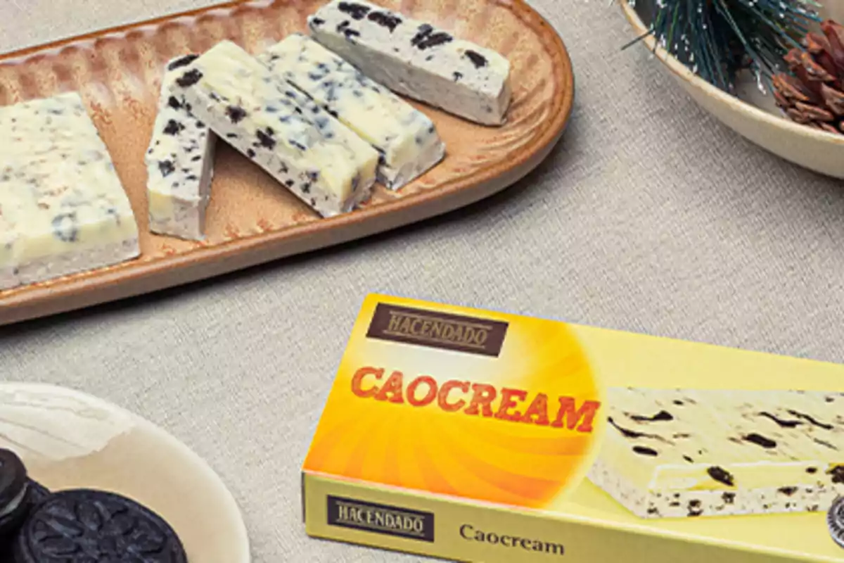 Torró de xocolata blanca amb galeta tipus oreo en una safata al costat de la seva capsa de la marca Hacendado sobre una taula Torró de xocolata blanca amb galeta tipus oreo en una safata al costat de la seva capsa de la marca Hacendado sobre una taula