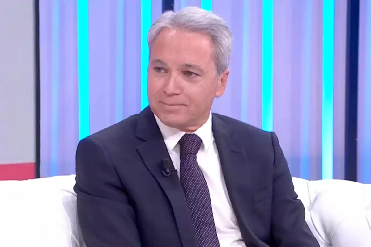 Vicente Vallés amb vestit fosc i corbata assegut en un sofà blanc en un plató de televisió amb llums blaves de fons. Captura de 'Y ahora Sonsoles' Vicente Vallés amb vestit fosc i corbata assegut en un sofà blanc en un plató de televisió amb llums blaves de fons. Captura de 'Y ahora Sonsoles'