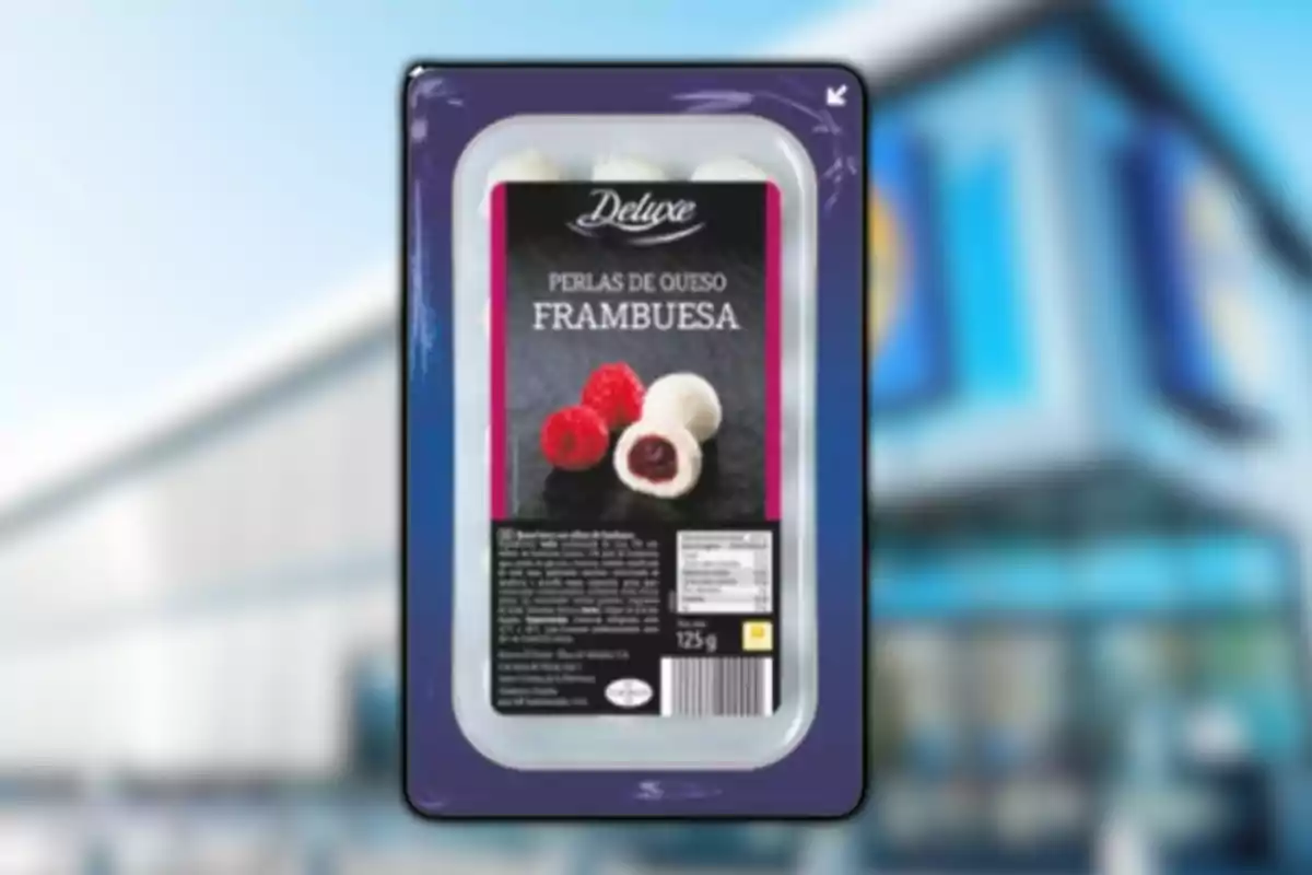 Envase de perlas de queso con frambuesa de la marca Deluxe frente a un fondo borroso de supermercado