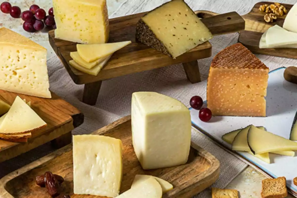 Variedad de quesos artesanales en tablas de madera acompañados de uvas, nueces y pan tostado