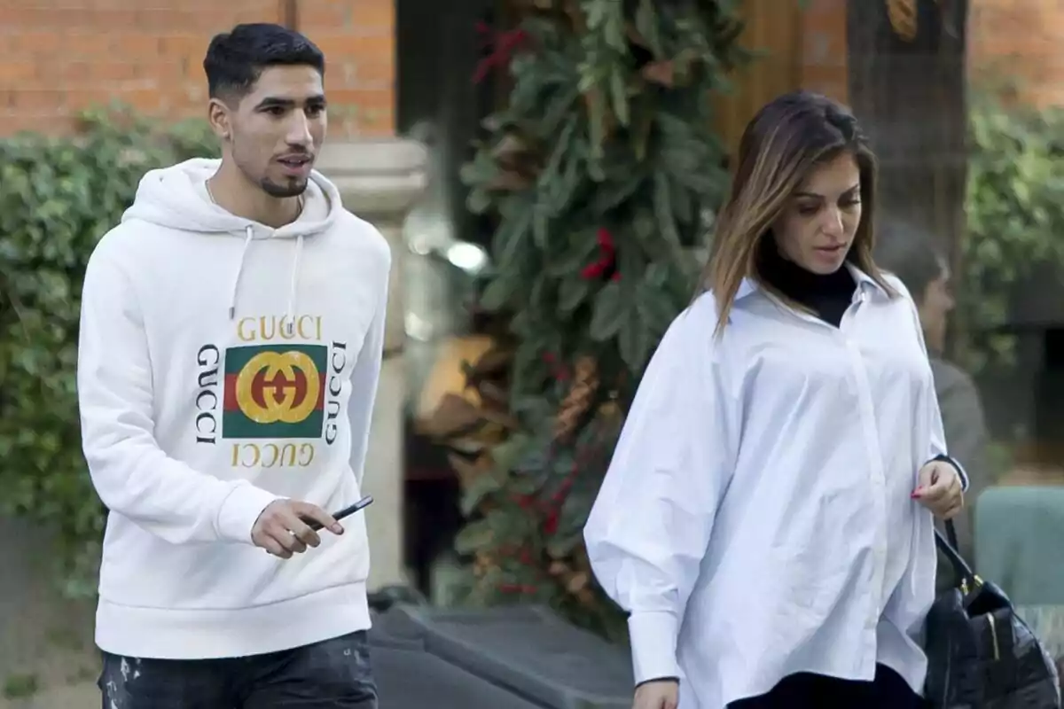 Achraf Hakimi y Hiba Abouk caminando por la calle, él lleva una sudadera blanca de Gucci y ella una camisa blanca suelta. Achraf Hakimi y Hiba Abouk caminando por la calle, él lleva una sudadera blanca de Gucci y ella una camisa blanca suelta.