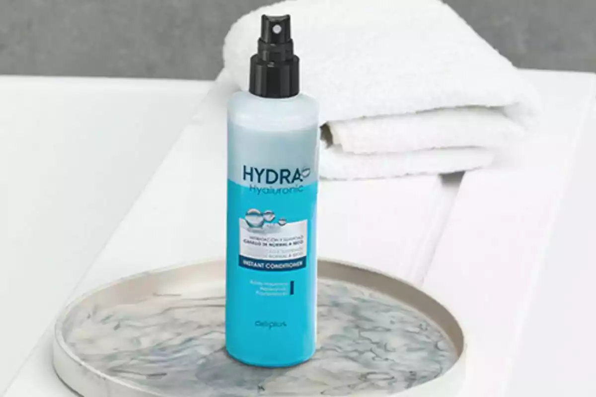 Ampolla de condicionador instantani Hydra Hyaluronic sobre una safata al costat de tovalloles blanques. Ampolla de condicionador instantani Hydra Hyaluronic sobre una safata al costat de tovalloles blanques.