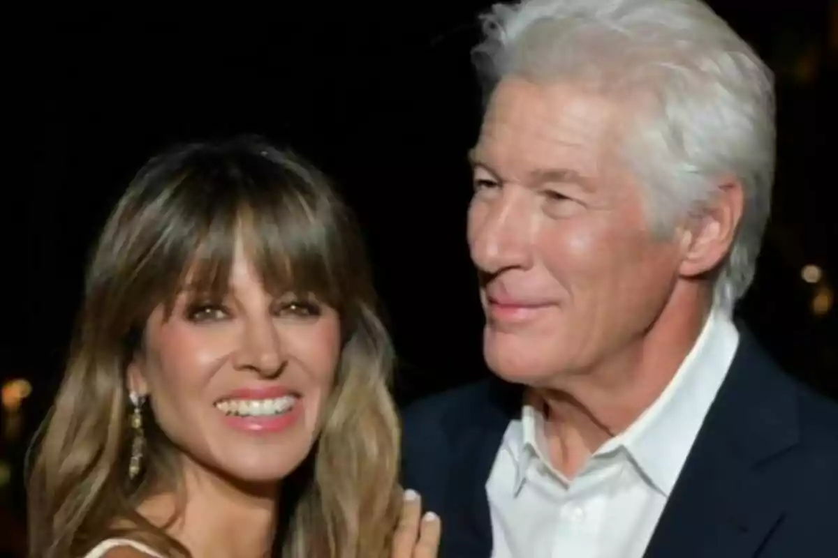Una parella —formada per Alejandra Silva i Richard Gere— somriu i posa junta en un esdeveniment elegant amb un fons fosc. Una parella —formada per Alejandra Silva i Richard Gere— somriu i posa junta en un esdeveniment elegant amb un fons fosc.