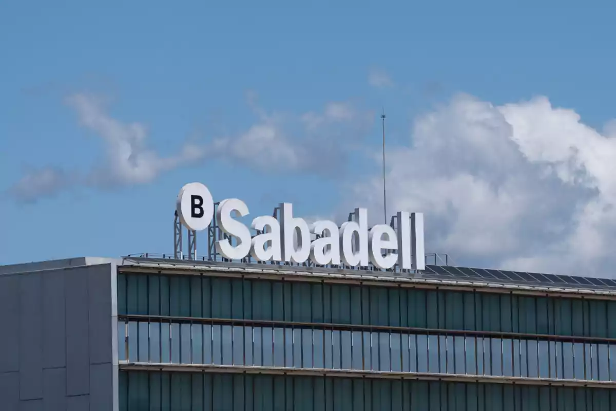 Edificio con el logotipo de Sabadell en la parte superior bajo un cielo azul con algunas nubes. Edificio con el logotipo de Sabadell en la parte superior bajo un cielo azul con algunas nubes.