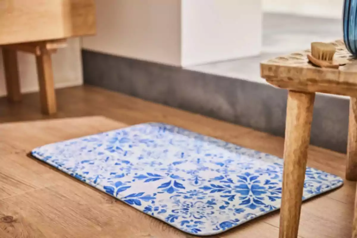 Una catifa amb disseny floral blau sobre un terra de fusta al costat d'un moble de fusta clara. Una catifa amb disseny floral blau sobre un terra de fusta al costat d'un moble de fusta clara.