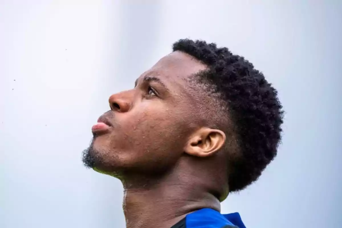 A man looking up with a pensive expression and a blurred background.