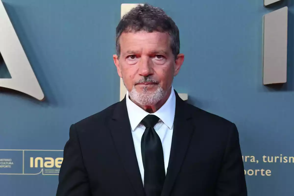 Antonio Banderas amb vestit negre i corbata en un esdeveniment formal amb fons blau. Antonio Banderas amb vestit negre i corbata en un esdeveniment formal amb fons blau.