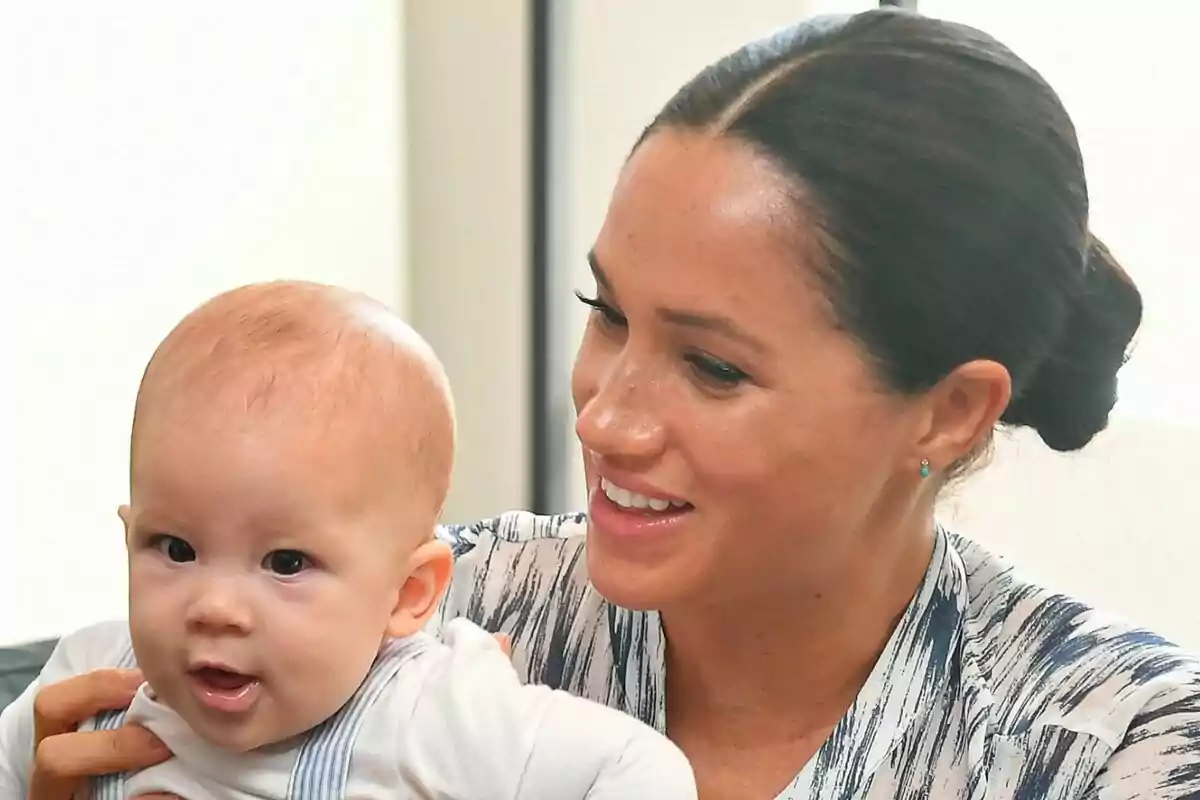Close-up of Meghan Markle smiling while holding her son, Archie, in her arms. Close-up of Meghan Markle smiling while holding her son, Archie, in her arms.