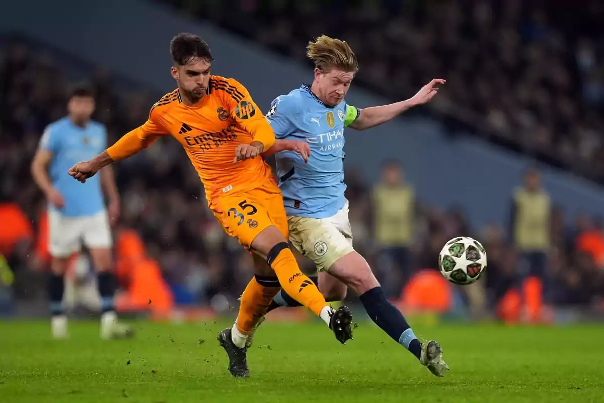 Two players compete for the ball in a match, one wearing orange and the other wearing light blue. Two players compete for the ball in a match, one wearing orange and the other wearing light blue.