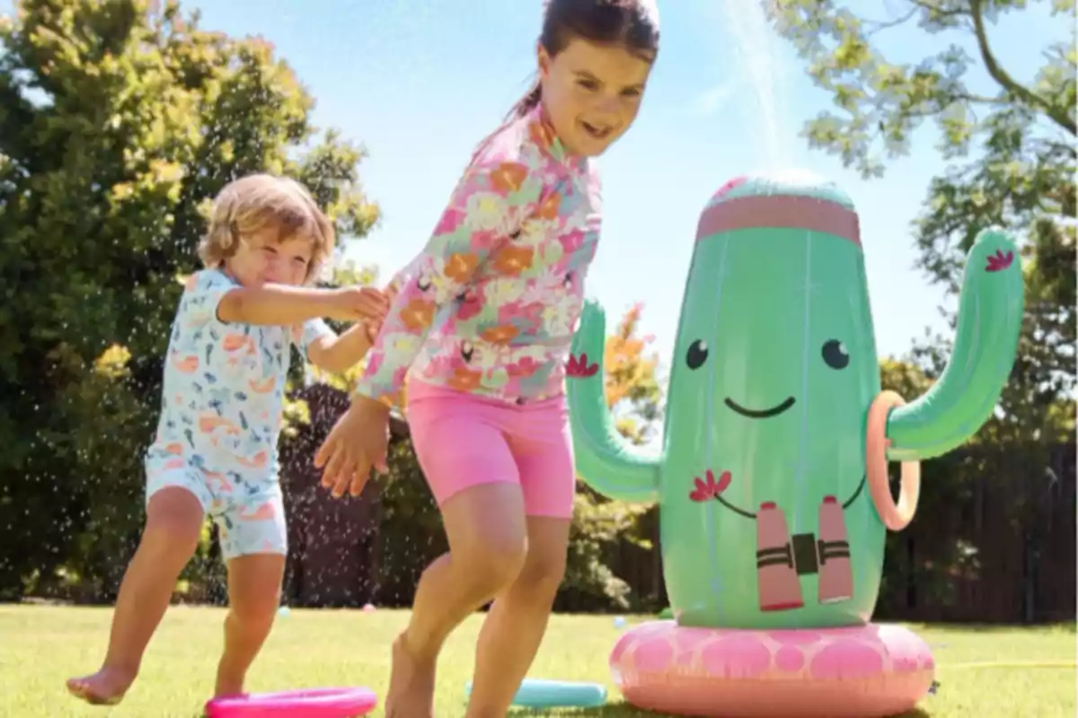 Nens jugant feliços amb un cactus inflable al jardí sota el sol. Nens jugant feliços amb un cactus inflable al jardí sota el sol.