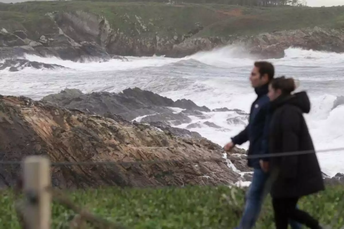 Una parella camina al costat del mar amb altes onades