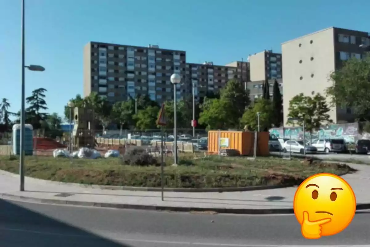 Una zona urbana con edificios residenciales altos al fondo, un área en construcción con una caseta de obra naranja y un emoji pensativo en primer plano. Una zona urbana con edificios residenciales altos al fondo, un área en construcción con una caseta de obra naranja y un emoji pensativo en primer plano.