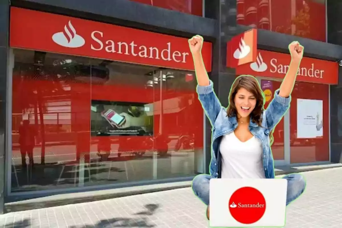 Dona feliç amb els braços aixecats davant d'una sucursal del banc Santander amb un ordinador portàtil.