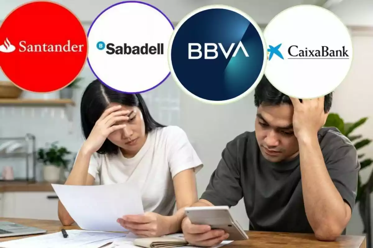 Una parella preocupada revisant documents financers amb logotips de bancs com Santander, Sabadell, BBVA i CaixaBank a la part superior.