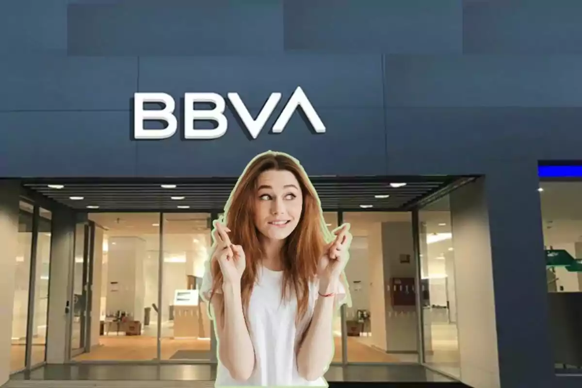 Una dona amb els dits creuats davant una sucursal del banc BBVA.