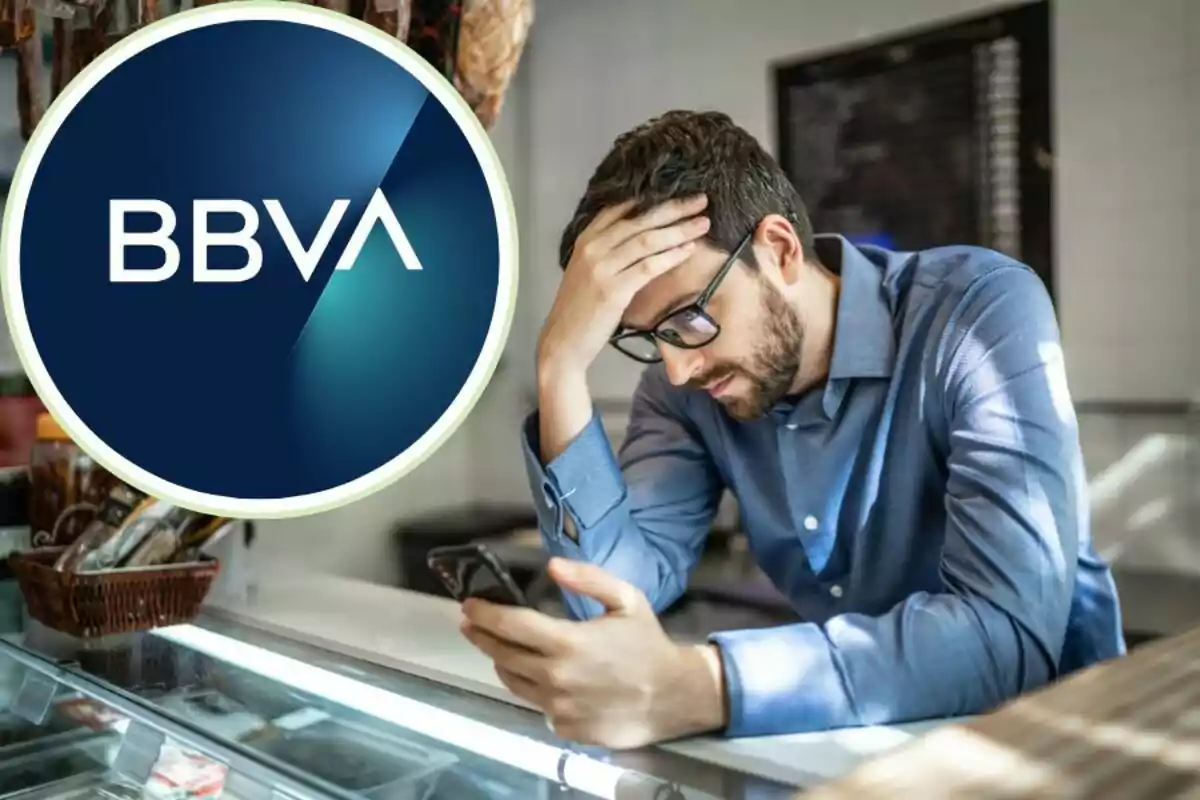 Home preocupat mirant el telèfon mòbil amb el logo de BBVA a la part superior esquerra.