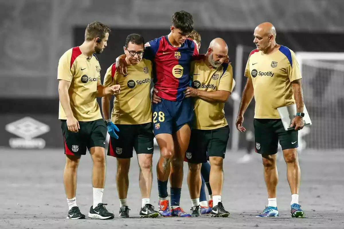 Un jugador de futbol del FC Barcelona és assistit pel personal mèdic de l?equip mentre surt del camp.