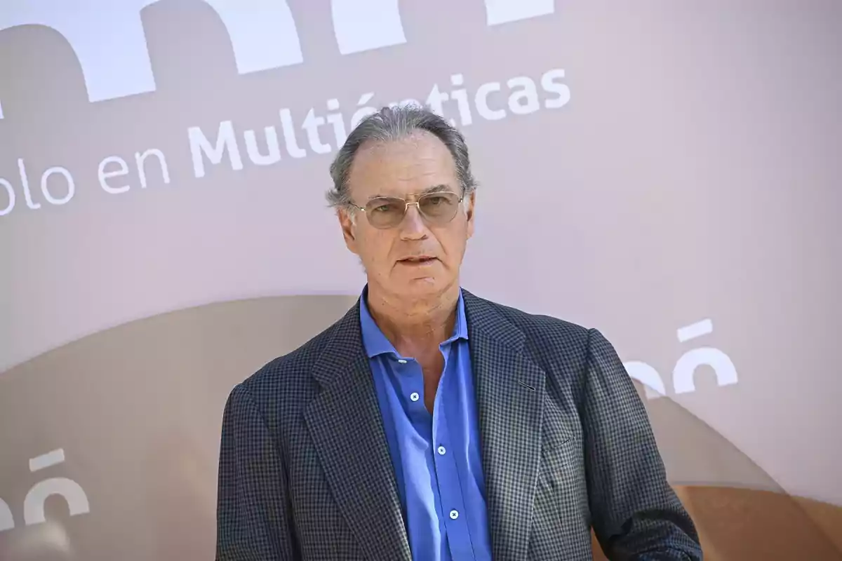 Bertín Osborne con camisa azul y saco a cuadros posando frente a un fondo con letras blancas. Bertín Osborne con camisa azul y saco a cuadros posando frente a un fondo con letras blancas.