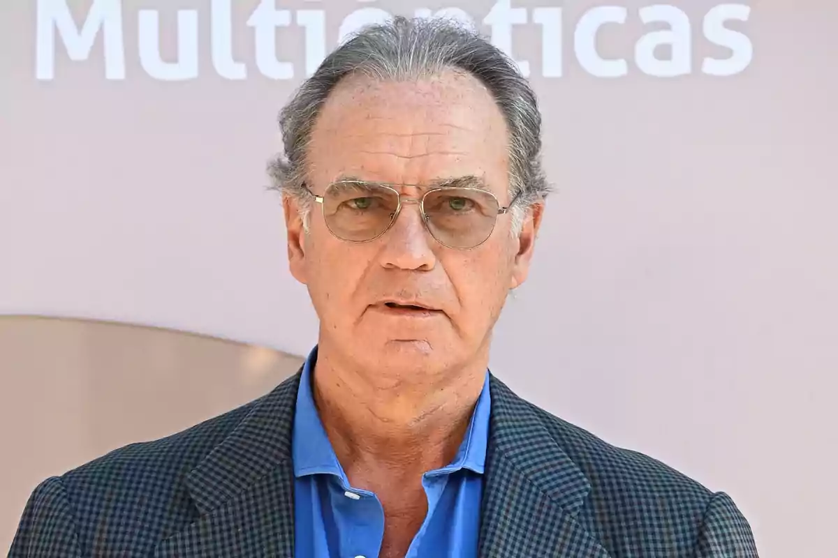 Bertín Osborne viste camisa azul y saco a cuadros frente a un fondo claro con letras borrosas Bertín Osborne viste camisa azul y saco a cuadros frente a un fondo claro con letras borrosas