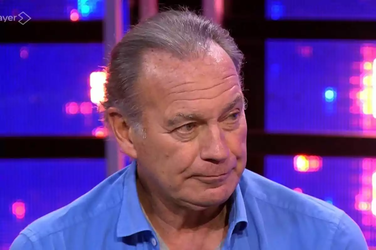 Bertín Osborne més gran amb camisa blava en un plató de televisió il·luminat amb llums de colors a Tu Cara Me Suena. Bertín Osborne més gran amb camisa blava en un plató de televisió il·luminat amb llums de colors a Tu Cara Me Suena.