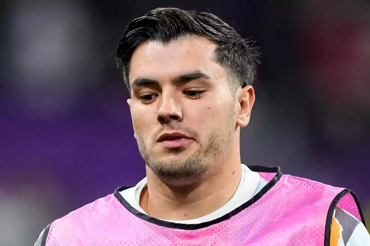 A man in a pink vest in a sports setting. A man in a pink vest in a sports setting.
