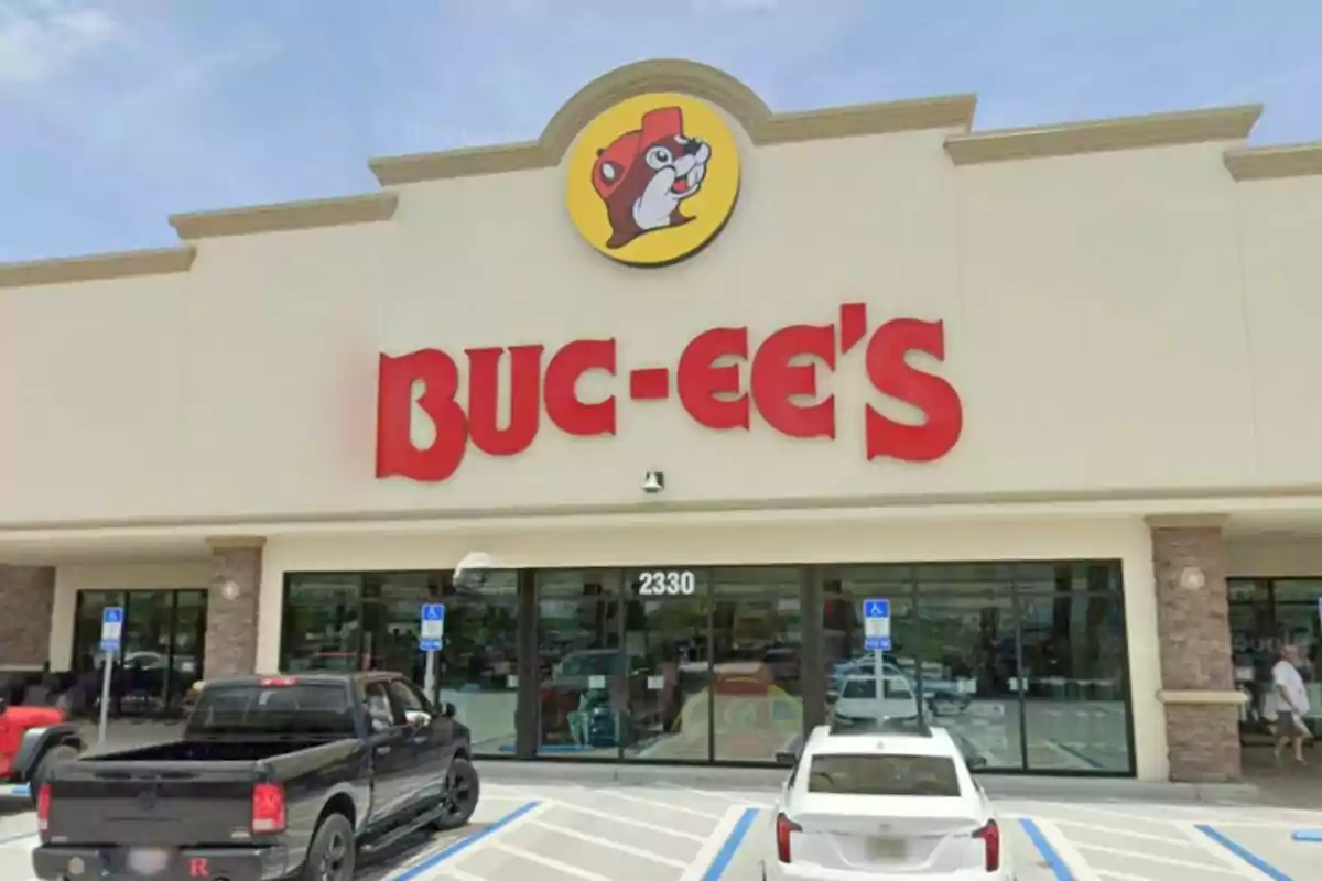 Façana d'una botiga Buc-ee's amb el seu logotip característic i diversos vehicles estacionats al davant. Façana d'una botiga Buc-ee's amb el seu logotip característic i diversos vehicles estacionats al davant.