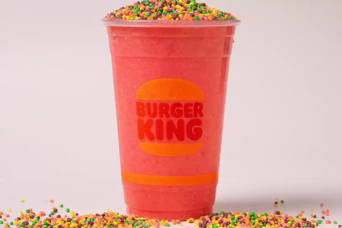 A glass of red drink from Burger King with colorful candies on top and around. A glass of red drink from Burger King with colorful candies on top and around.