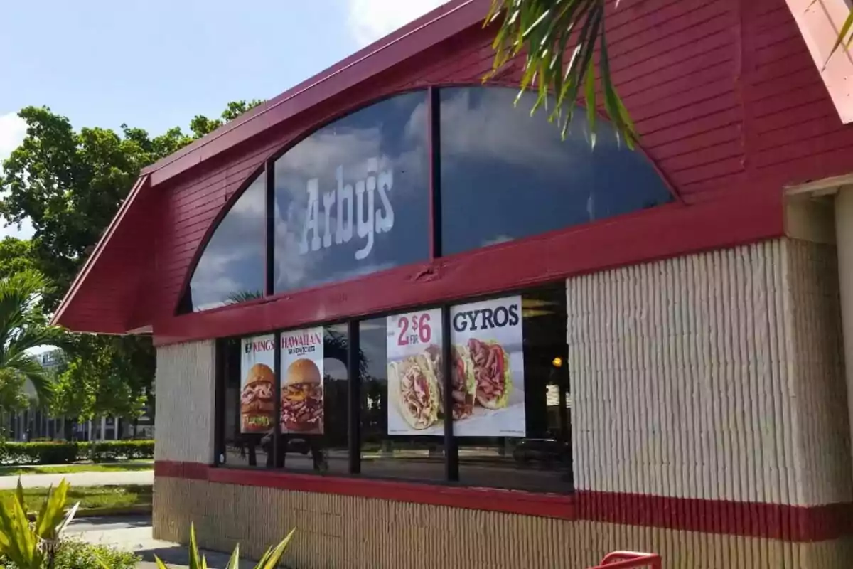 Un restaurante de comida rápida con carteles promocionales en las ventanas y un letrero grande en la parte superior. Un restaurante de comida rápida con carteles promocionales en las ventanas y un letrero grande en la parte superior.