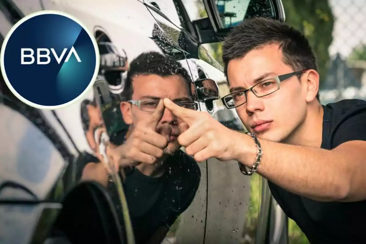 Un home amb ulleres inspecciona de prop la superfície d'un automòbil, mentre el logotip de BBVA apareix a la part superior esquerra de la imatge. Un home amb ulleres inspecciona de prop la superfície d'un automòbil, mentre el logotip de BBVA apareix a la part superior esquerra de la imatge.