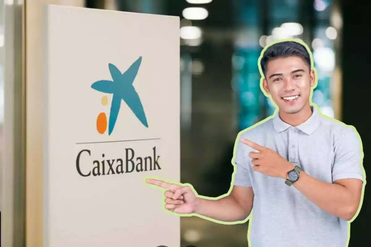 Un home somrient amb una camisa grisa assenyala un cartell de CaixaBank.