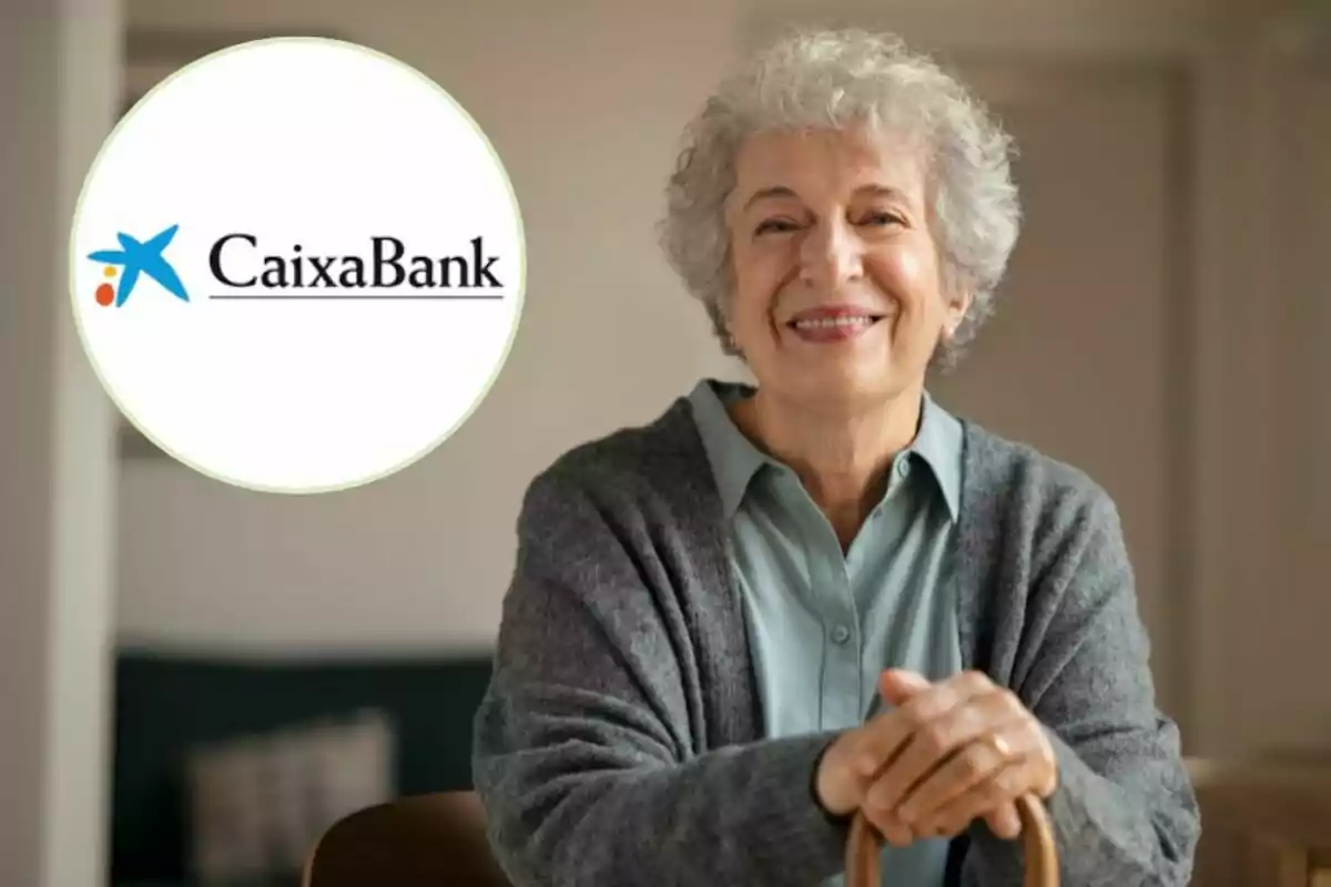 Una dona gran somrient amb cabell canós i un suèter gris, recolzada en un bastó, amb el logotip de CaixaBank a la cantonada superior esquerra. Una dona gran somrient amb cabell canós i un suèter gris, recolzada en un bastó, amb el logotip de CaixaBank a la cantonada superior esquerra.