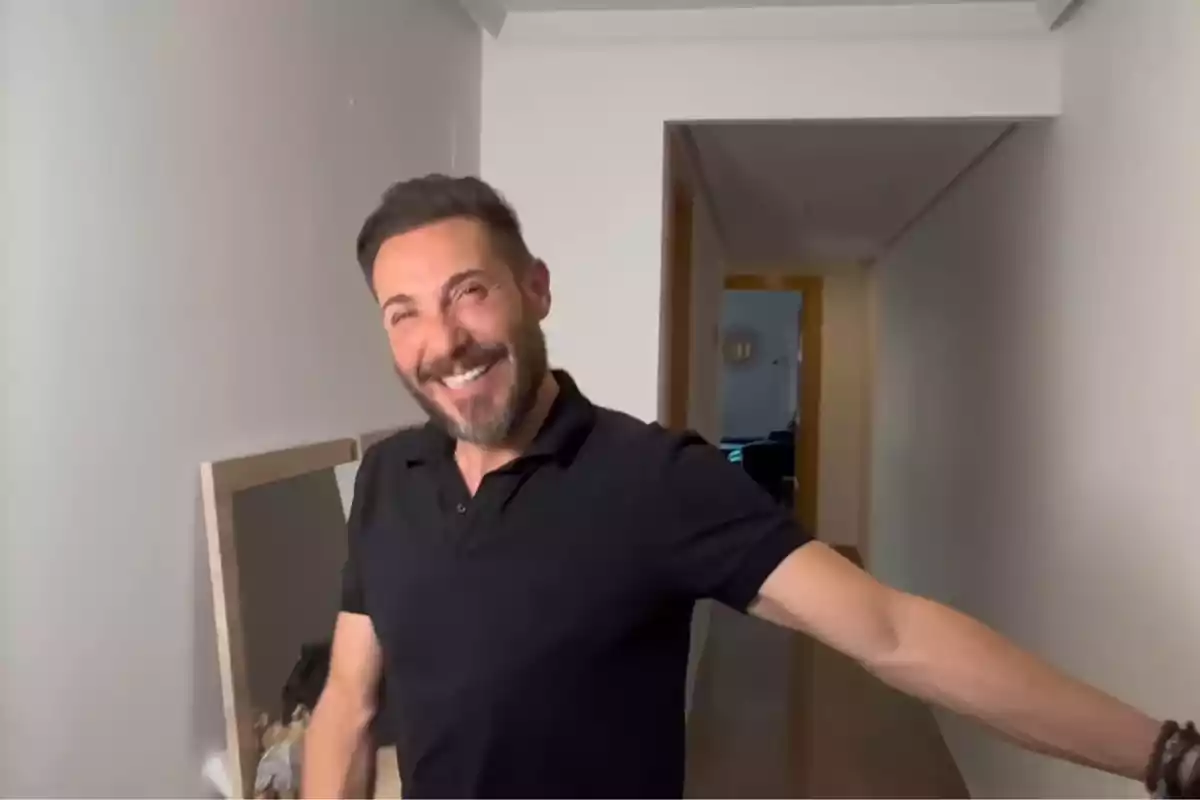 Antonio David Flores somrient amb barba i samarreta negra posant en un passadís d’una casa Antonio David Flores somrient amb barba i samarreta negra posant en un passadís d’una casa