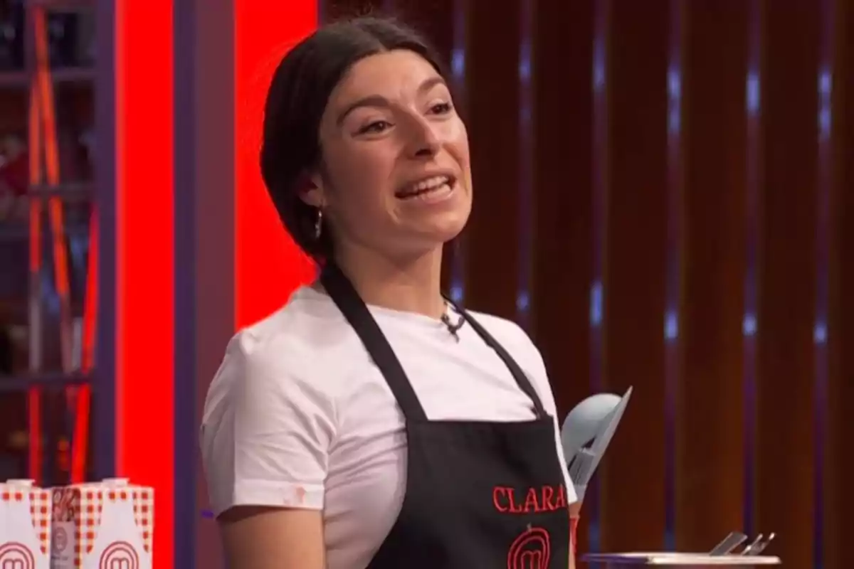 Clara amb davantal negre i samarreta blanca participant a 'Masterchef' mentre somriu i parla Clara amb davantal negre i samarreta blanca participant a 'Masterchef' mentre somriu i parla
