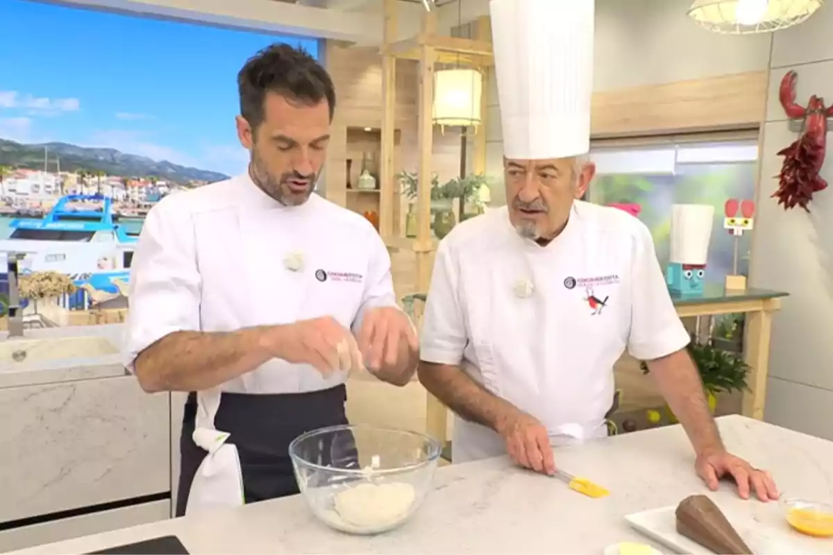 Karlos i Joseba Arguiñano amb uniforme blanc preparen una recepta en una cuina moderna mentre Joseba amassa en un bol de vidre i Karlos observa amb atenció. Karlos i Joseba Arguiñano amb uniforme blanc preparen una recepta en una cuina moderna mentre Joseba amassa en un bol de vidre i Karlos observa amb atenció.