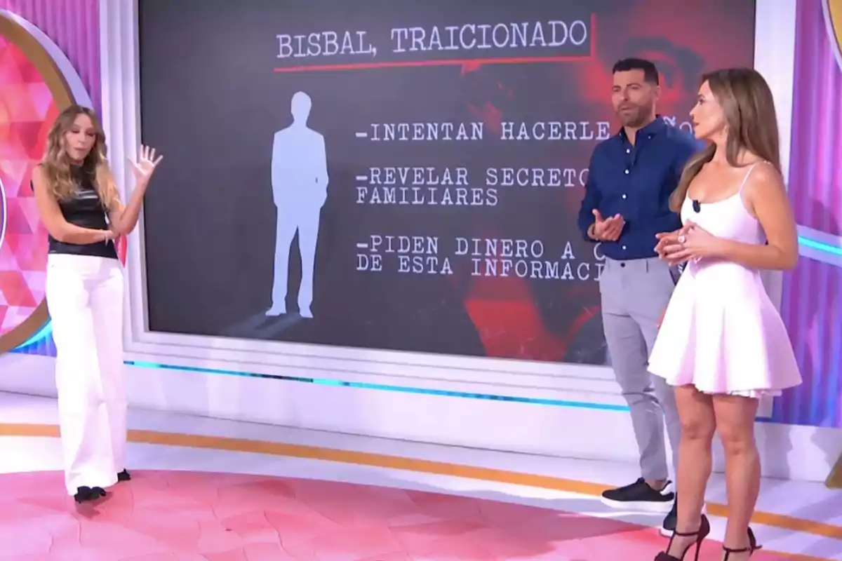 Tres persones estan dempeus en plató de 'Socialité' davant d'una pantalla que mostra text sobre una figura anònima i esmenta temes de traïció i secrets familiars. Tres persones estan dempeus en plató de 'Socialité' davant d'una pantalla que mostra text sobre una figura anònima i esmenta temes de traïció i secrets familiars.