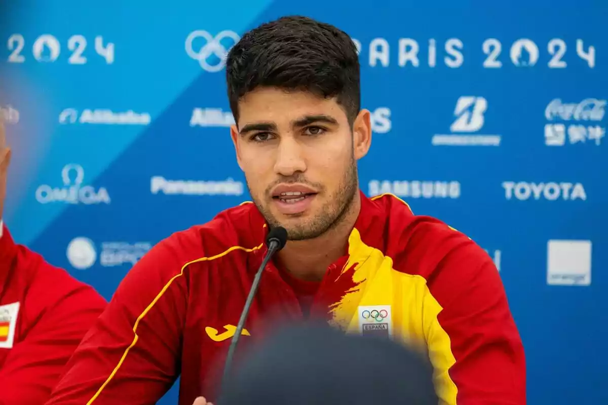 Carlos Alcaraz en una conferència de premsa amb el logo dels Jocs Olímpics de París 2024 al fons. Carlos Alcaraz en una conferència de premsa amb el logo dels Jocs Olímpics de París 2024 al fons.
