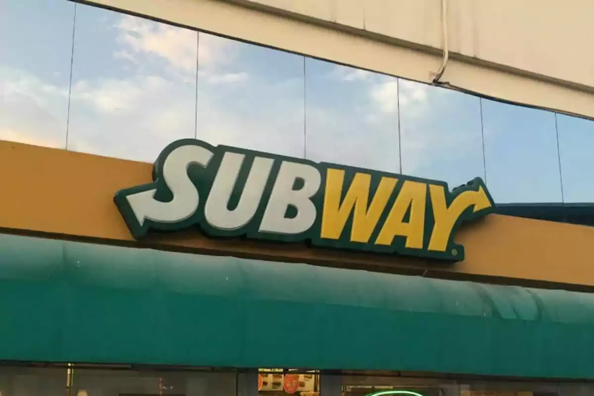 A Subway sign, a fast-food restaurant, with a background of sky and clouds. A Subway sign, a fast-food restaurant, with a background of sky and clouds.
