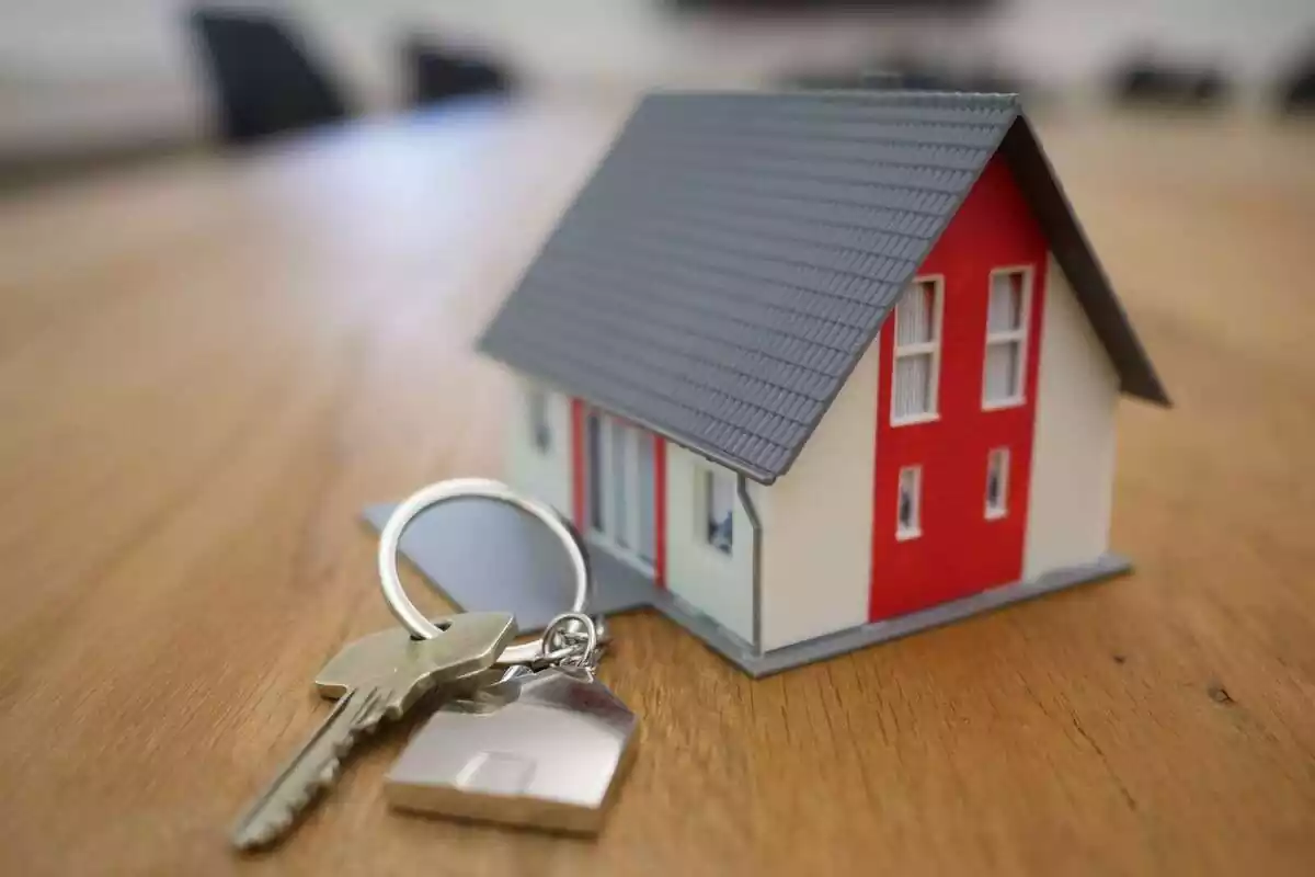 Una maqueta d´una casa en miniatura al costat d´unes claus en una taula