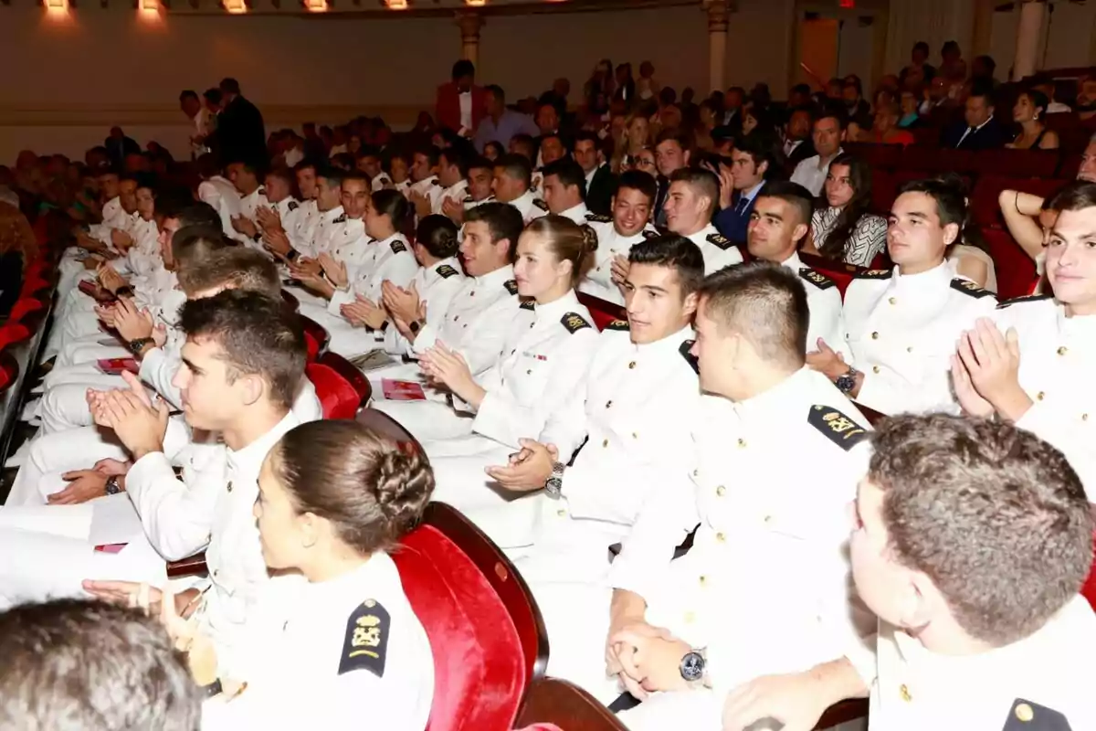 Grup de cadets vestits amb uniformes blancs asseguts en un auditori aplaudint durant un esdeveniment formal Grup de cadets vestits amb uniformes blancs asseguts en un auditori aplaudint durant un esdeveniment formal